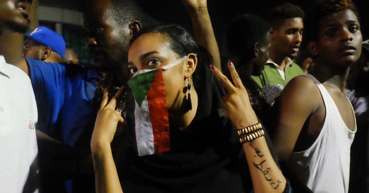 Sudanska ženska na protestu, na obrazu ima sudansko zastavo.