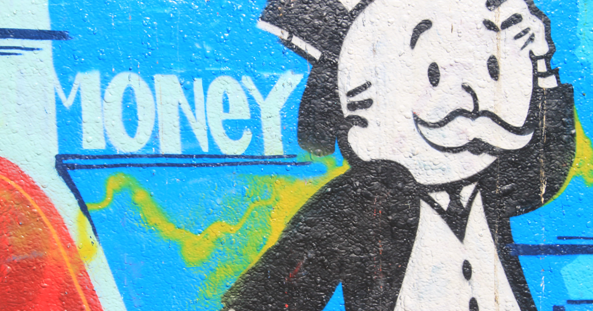 Monopoly striček, ki se drži za glavo. Za njim je napis