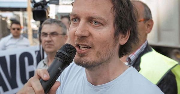 Fotografija Gorana Lukića iz Delavske svetovalnice, ki v rokah drži mikrofon na shodu.