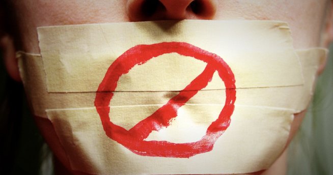 Ženska, ki ima prelepljena usta in na traku narisan stop znak.