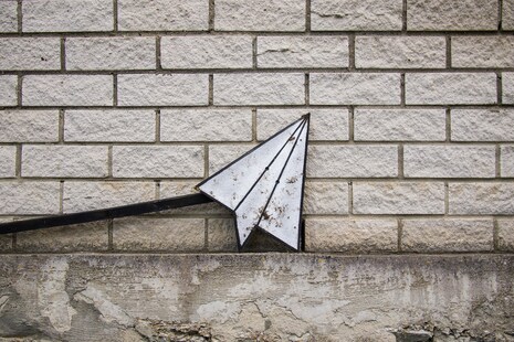 un avion en papier sur un mur de briques