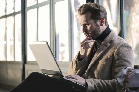 un homme devant son ordinateur se posant une question