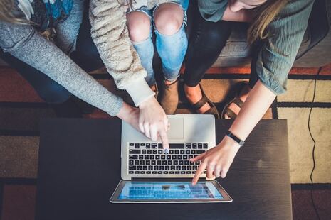 trois personnes pointant à un ordinateur en signe de collaboration
