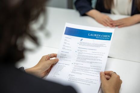 une personne tenant son CV des deux mains