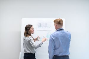 un homme et une femme devant un tableau blanc