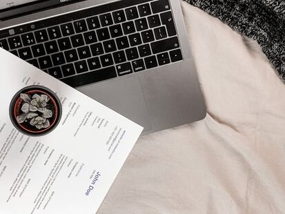 photo d'un ordinateur ouvert avec un CV sur le clavier