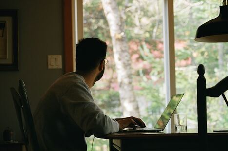 personne travaillant depuis la maison et regardant par la fenêtre de son appartement