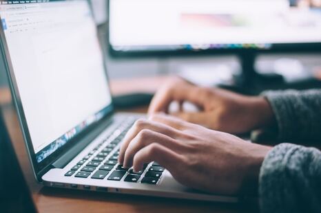 main d'un homme écrivant sur un clavier d'ordinateur