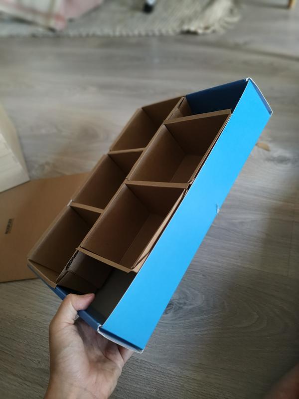 Une main qui tient une boîte divisée en 5 sections. La boîte fait environ 15cm de hauteur, 40cm de longueur et 20cm de largeur.