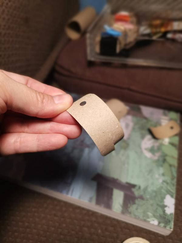 Une main qui tient un petit rectangle de carton perforé. 