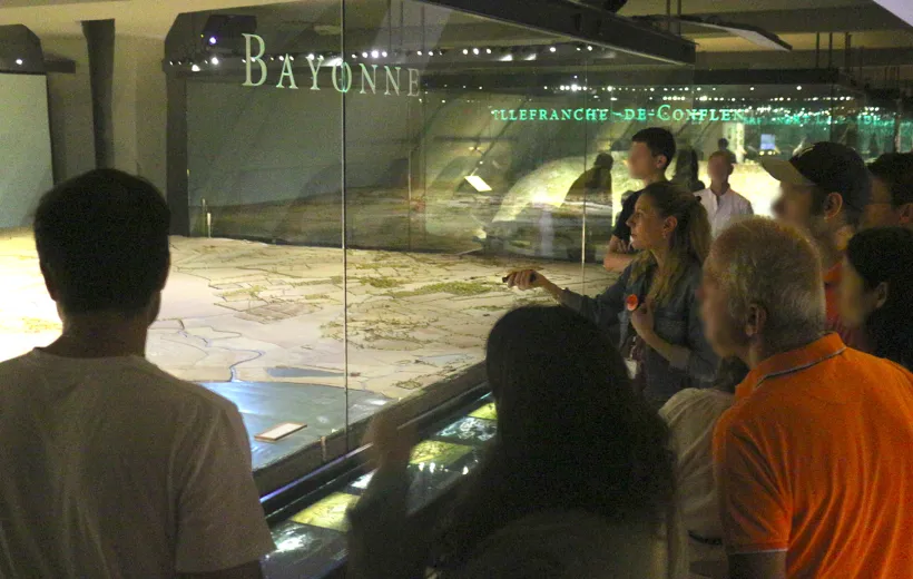 Une conférencière montre la maquette de Bayonne à un groupe de visiteurs.