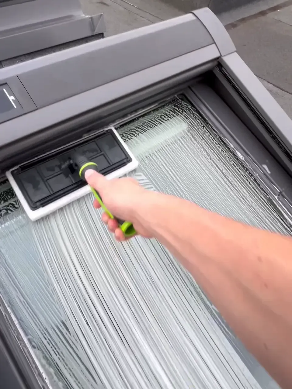 Étape de récurage d'une fenêtre de toit avec un pad spécialisé et une solution nettoyante pour désincruster les saletés sans rayer le verre - Intervnetion Optipropre