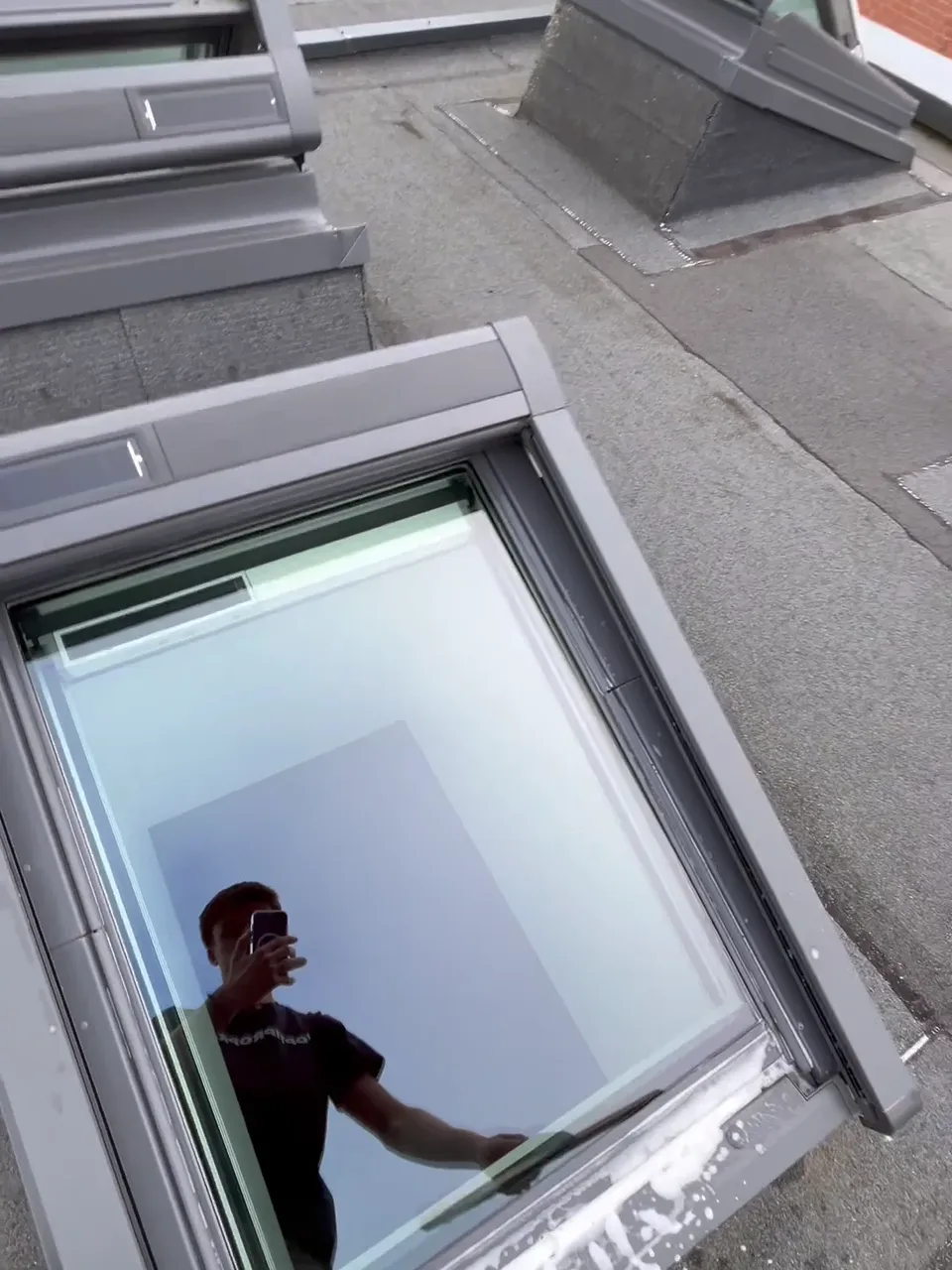 Finition impeccable d'un Velux : passage de la raclette professionnelle pour un séchage sans traces et une transparence parfaite de la vitre - Réalisation Optipropre