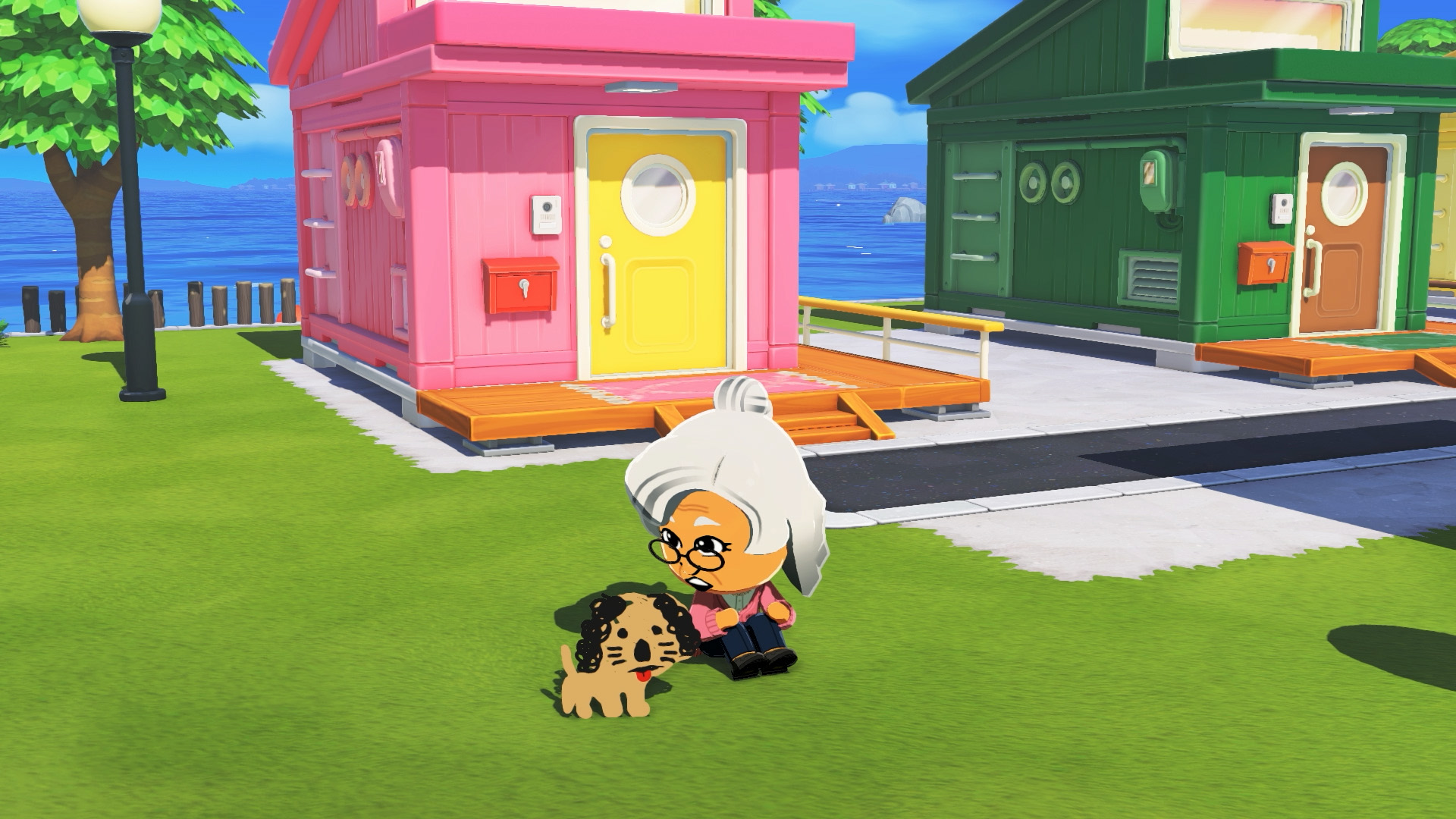 Un Mii assis dans l'herbe caresse un chien devant les maisons de l'île dans Tomodachi Life : Une vie de rêve