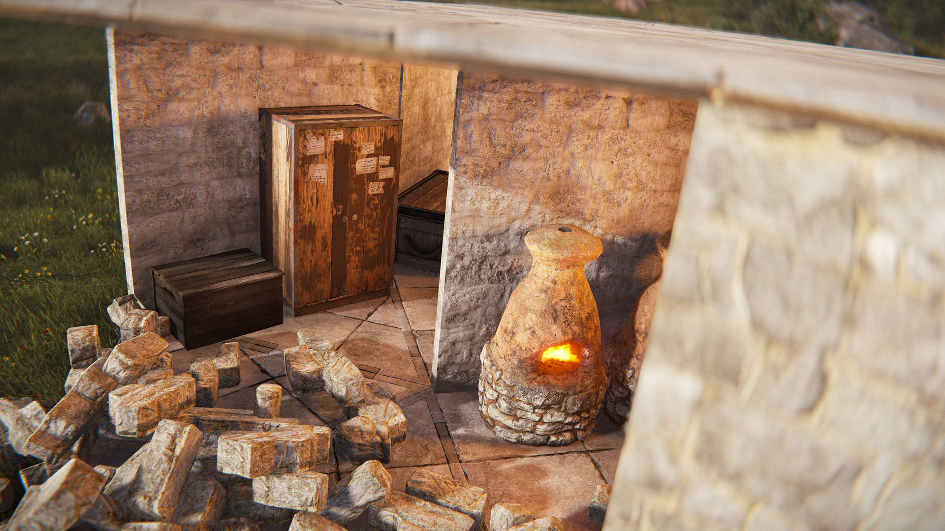 Intérieur d'une base en pierre partiellement détruite dans Rust, avec une Armoire à outils, un coffre en bois et un four en pierre