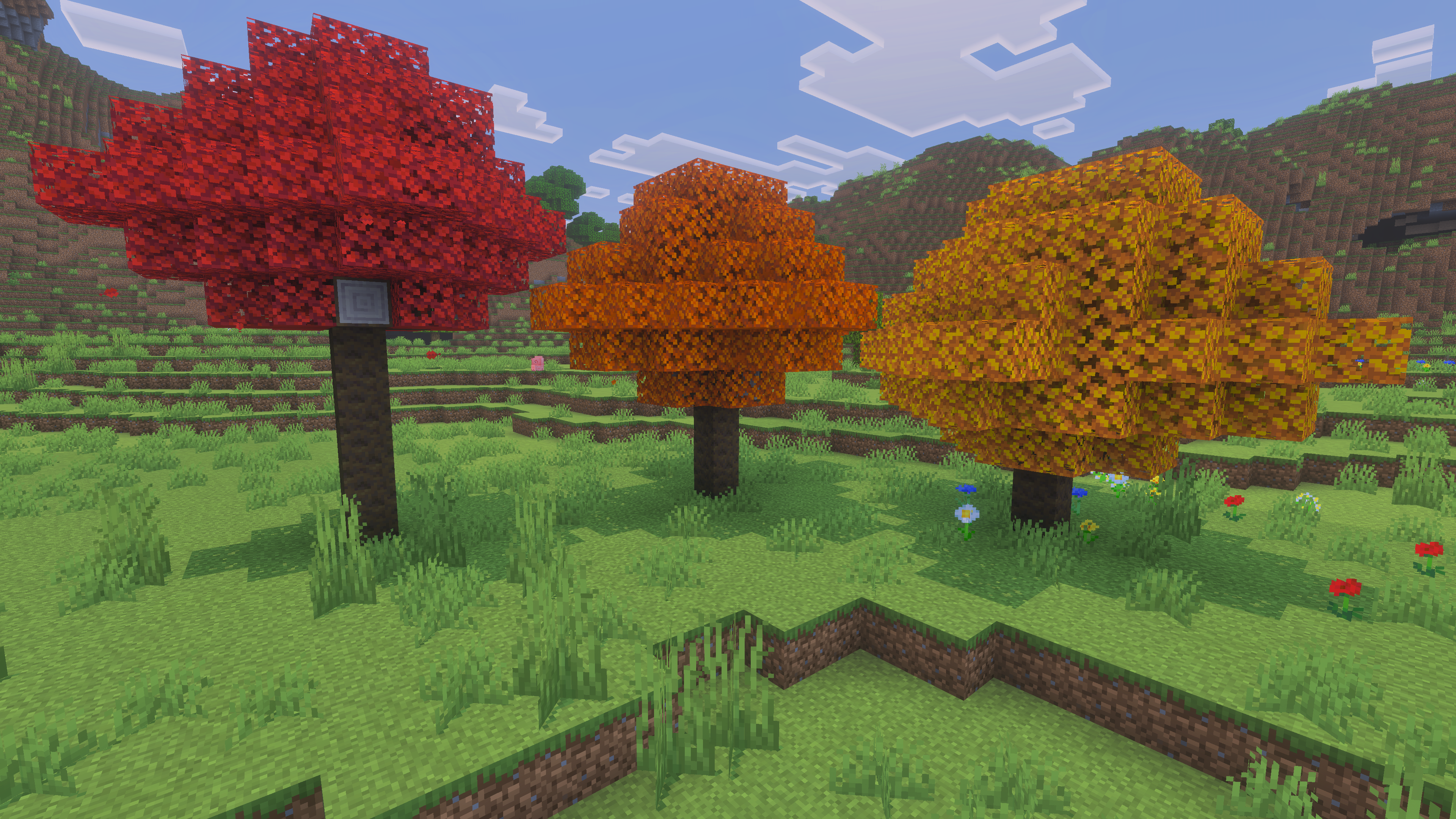 Les trois variantes de peuplier de Minecraft 26.3 côte à côte : feuillages rouge, orange et jaune sur des troncs clairs
