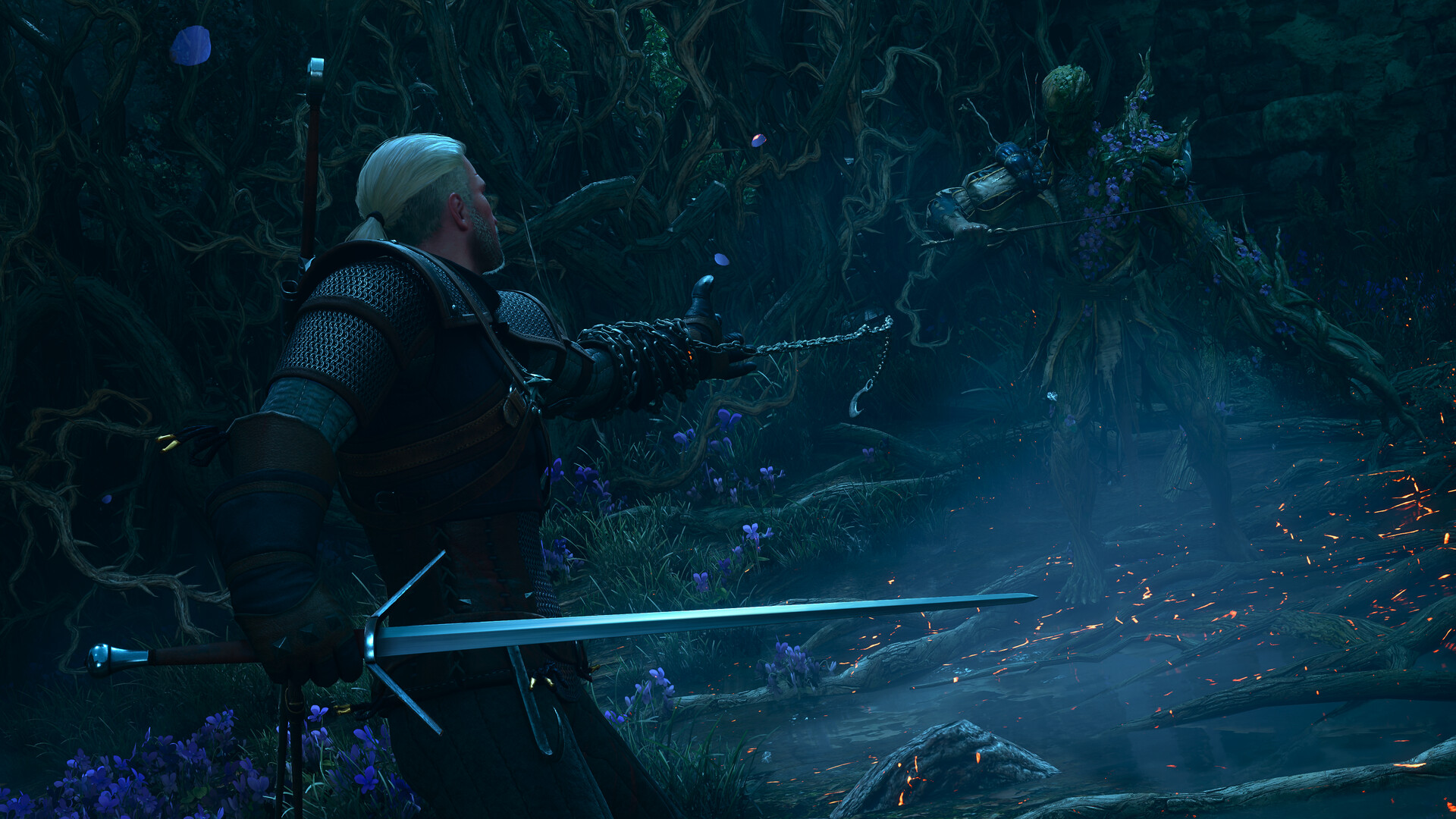 Geralt lance une chaîne vers une créature végétale couverte de fleurs bleues dans un sous-bois nocturne, son épée dans l'autre main