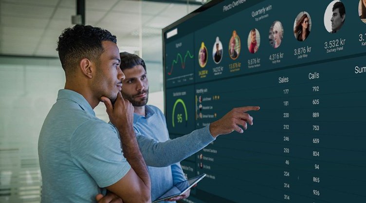 Blog - Before You Start Using Dashboards - Two employees looking at a Plecto dashboard in the office