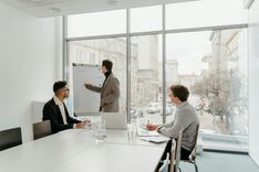 Three professionals engaged in a business meeting in a bright conference room.