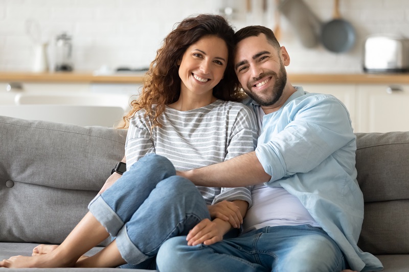 Portrait of couple posing photo shooting seated on couch indoors